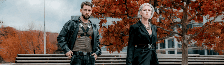 Ein Mann und eine Frau im Rave-Outfit mit Harness, massivem Schmuck und Gürtel